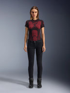 Alpinestars Daisy V3 Women's Riding Denim, Noir, pantalon de moto coupe slim, porté par un mannequin avec un t-shirt technique à motifs rouges et noirs et des bottes de moto noires, équipement urbain décontracté avec une silhouette féminine et une taille haute.