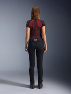 Alpinestars Daisy V3 Women's Riding Denim, Noir Rinse, pantalon de moto coupe slim vu de dos, doté d'une taille haute et de poches arrière, associé à un haut technique à motifs rouge et noir et des bottes noires, équipement de moto urbain pour femme