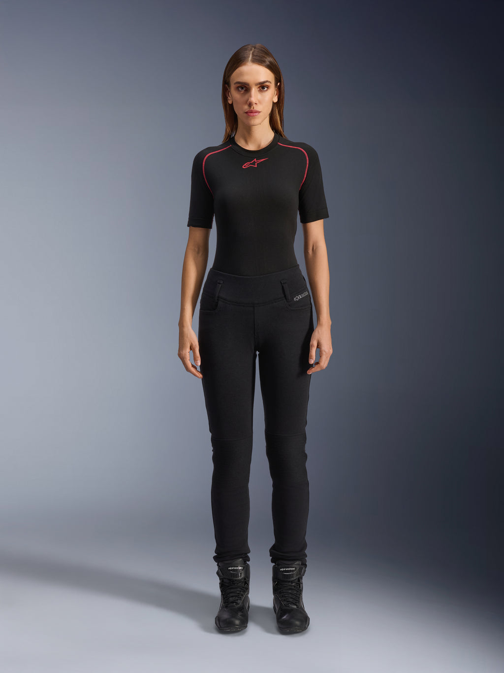 Leggings Banshee Femme Alpinestars, leggings de moto noirs, coupe anatomique moulante, portés par un mannequin femme avec une couche de base noire et des bottes de moto, avec panneaux de genoux côtelés et taille haute pour la conduite urbaine