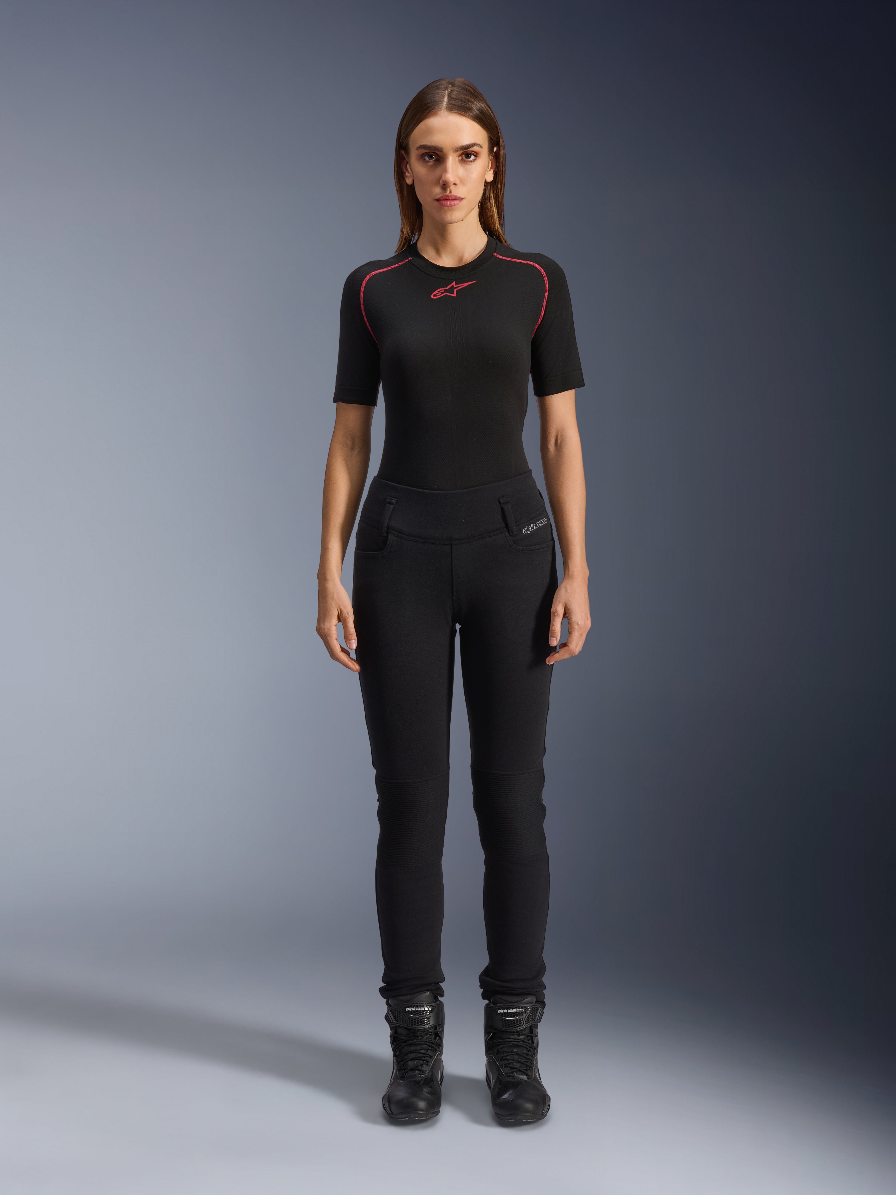 Leggings Banshee Femme Alpinestars, leggings de moto noirs, coupe anatomique moulante, portés par un mannequin femme avec une couche de base noire et des bottes de moto, avec panneaux de genoux côtelés et taille haute pour la conduite urbaine