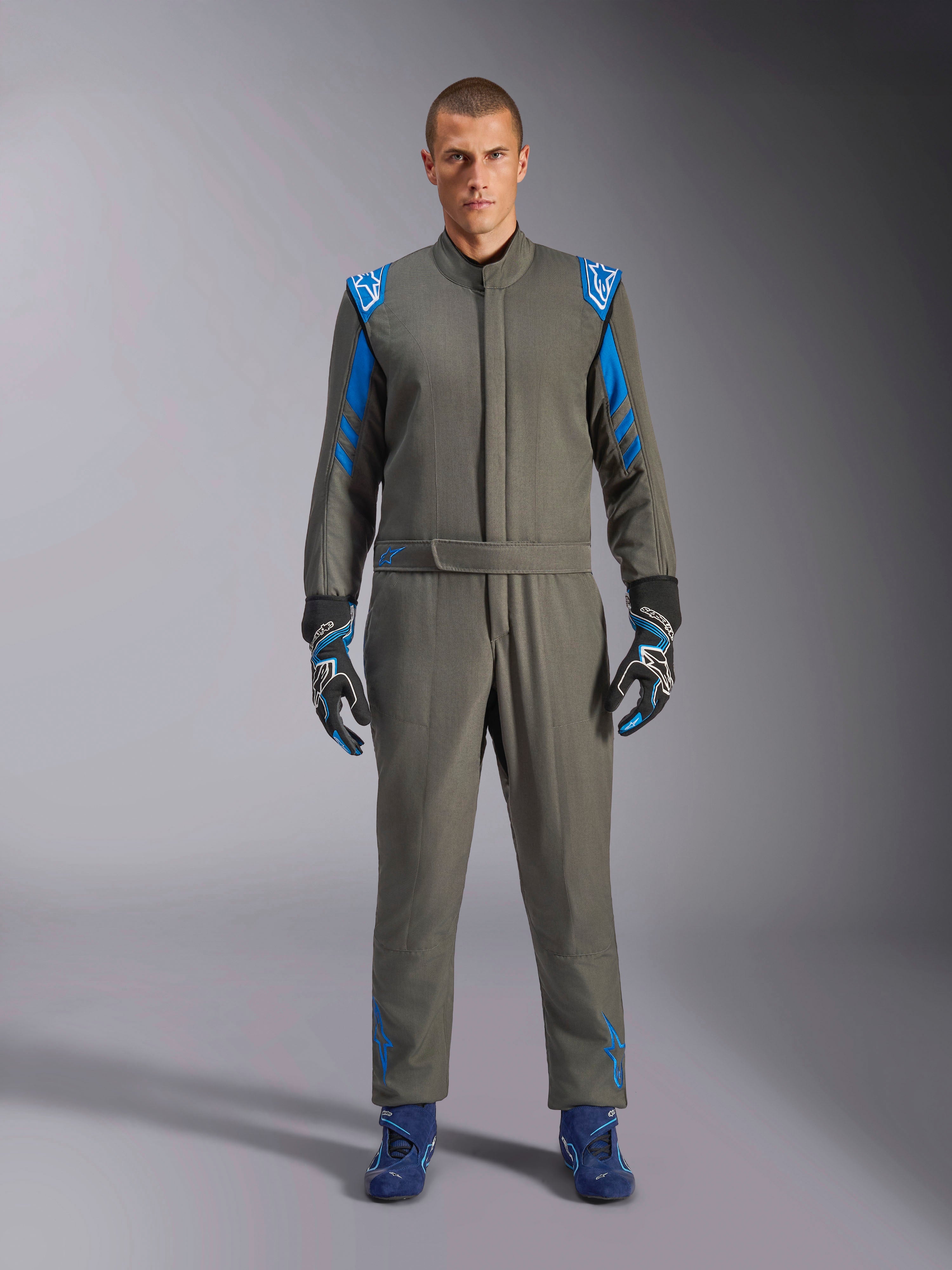 Alpinestars GP Race V3 Suit FIA, combinaison de course automobile bleu anthracite, portée avec des gants et des chaussures de course assortis, dotée d'épaulettes et de rayures sur les manches bleu vif, détails du logo Alpinestars, protection professionnelle de sport automobile pour la compétition sur circuit