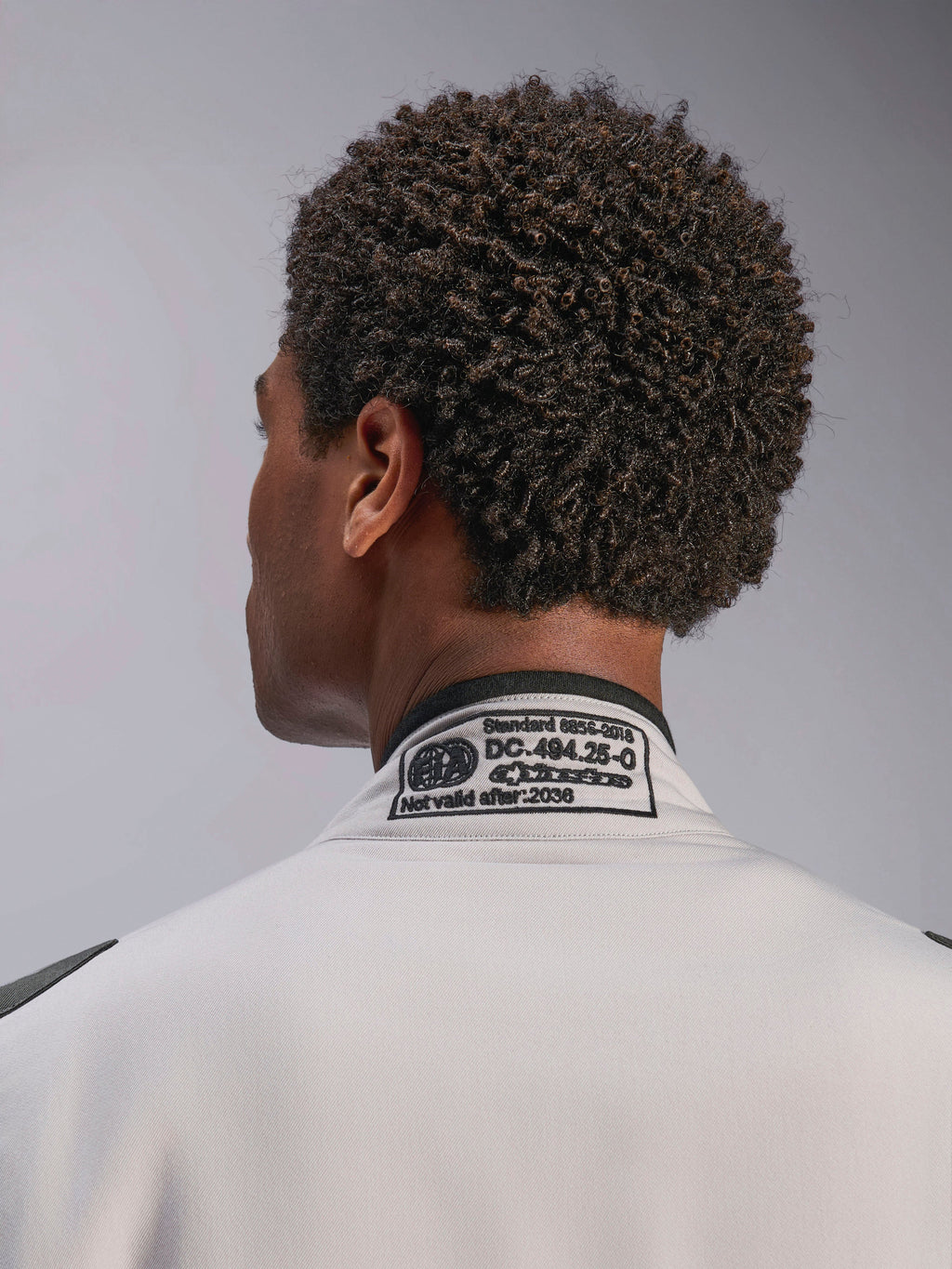 Combinaison Alpinestars GP Race V3 FIA, Silver Anthracite, gros plan sur le col arrière présentant l'étiquette de certification FIA 8856-2018 brodée, détaillant la conformité de sécurité pour l'équipement de course automobile