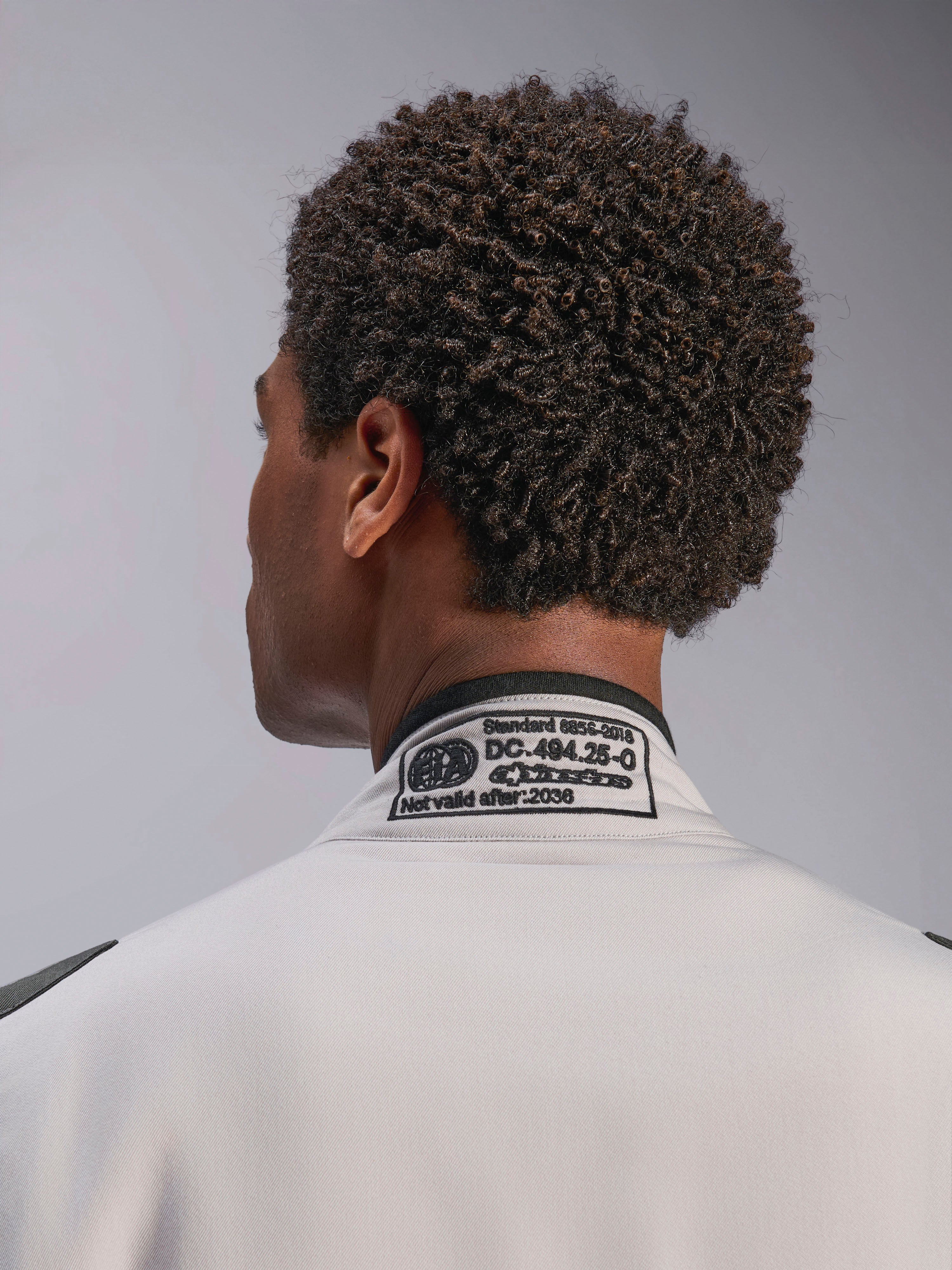 Combinaison Alpinestars GP Race V3 FIA, Silver Anthracite, gros plan sur le col arrière présentant l'étiquette de certification FIA 8856-2018 brodée, détaillant la conformité de sécurité pour l'équipement de course automobile