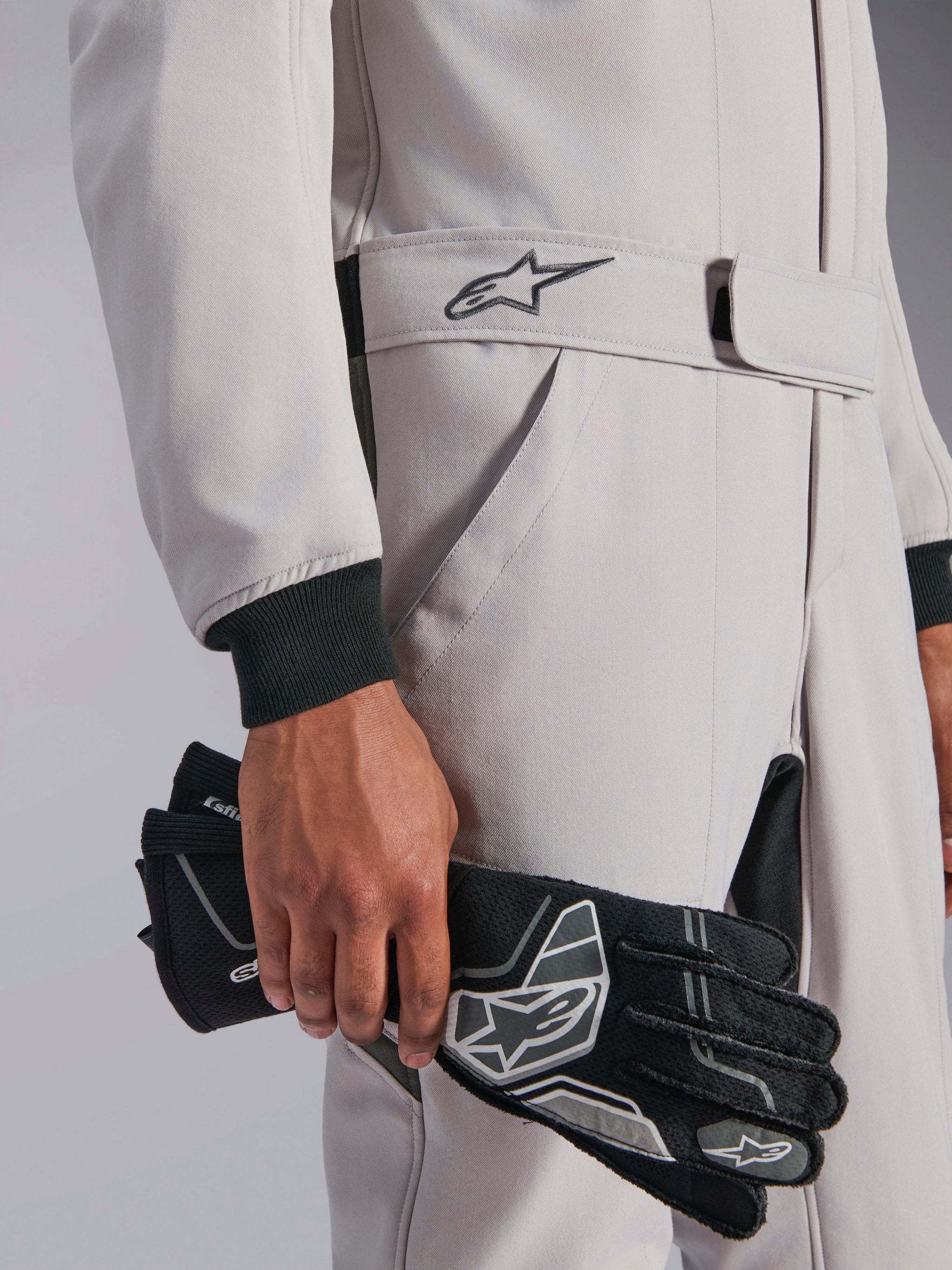 Combinaison Alpinestars GP Race V3 FIA, combinaison de course automobile, Argent Anthracite, tenue avec des gants de course noirs, dotée d'une taille ceinturée ajustable avec logo étoile brodé, poignets côtelés noirs, design sport automobile épuré et professionnel