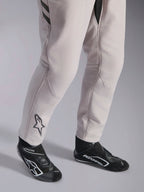 Alpinestars GP Race V3 Suit FIA, combinaison de course automobile Silver Anthracite, vue détaillée du bas des jambes et des bottines de course noires, avec le logo Astars noir sur le mollet, équipement de sport automobile professionnel avec bords-côtes.