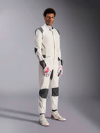 Mannequin homme portant la combinaison Alpinestars Hypertech V3, blanche avec des accents noirs et argentés, équipement de course automobile professionnel doté de panneaux noirs sur les épaules et les genoux, assorti de gants de course blancs et rouges et de bottines de course blanches