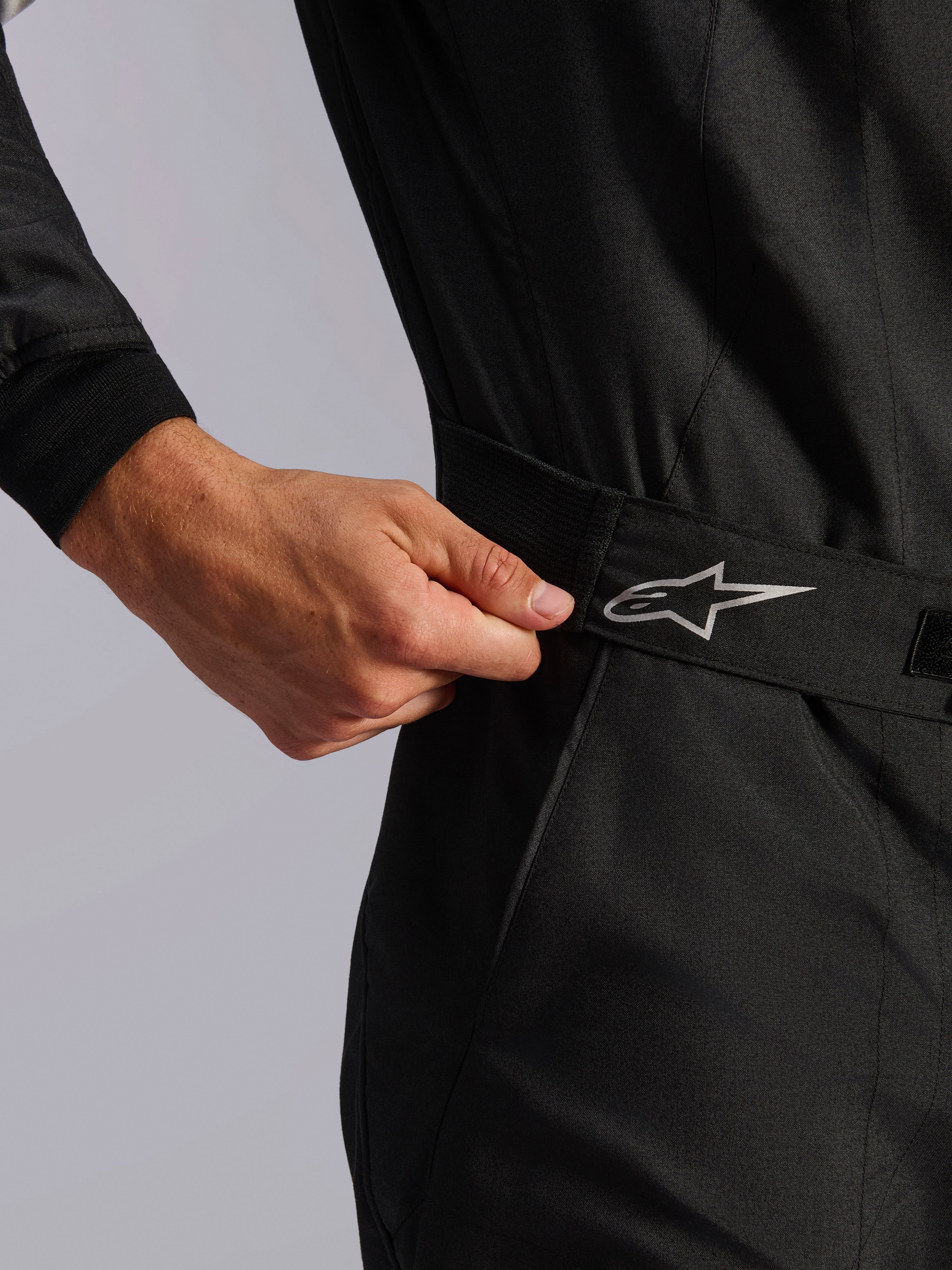 Combinaison Alpinestars Édition Limitée Lamborghini GP Tech V4 FIA, combinaison de course automobile, noire, gros plan sur la taille élastiquée ajustée à la main pour un ajustement précis, avec un logo Alpinestars argenté sur la ceinture