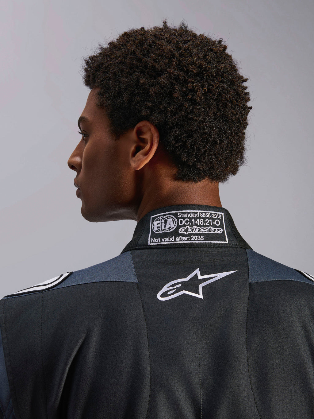Alpinestars GP Pro Comp V2 FIA, combinaison de course auto, noire et asphalte, certifiée FIA 8856-2018, logo Astar blanc.