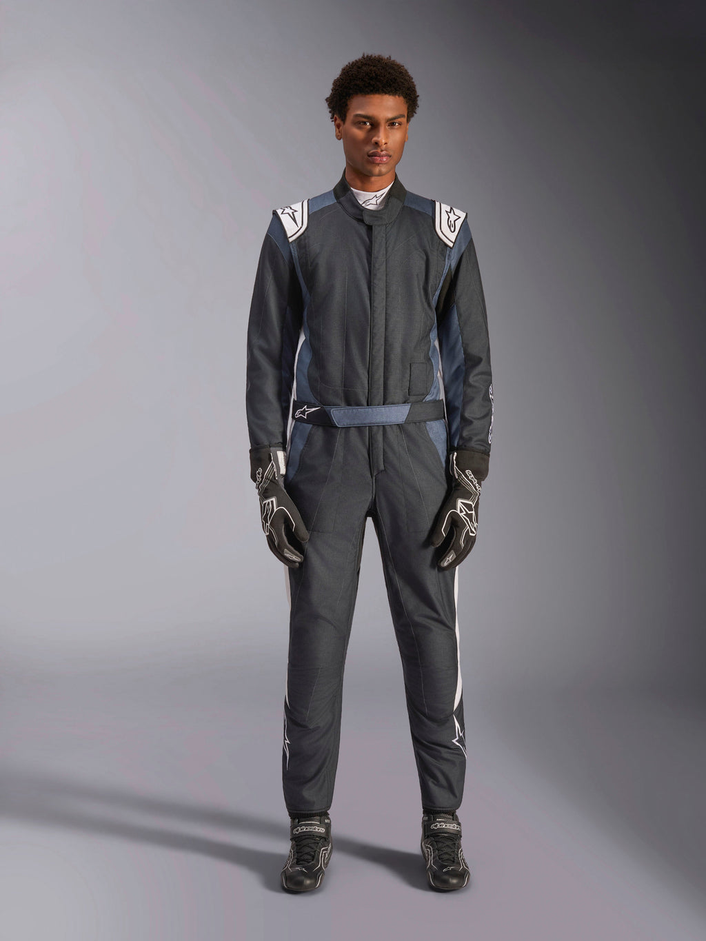 Alpinestars GP Pro Comp V2 - FIA, combinaison de course automobile pour homme, noire et blanche, certifiée FIA, portée par un pilote avec gants et bottes assortis pour la conduite sur circuit