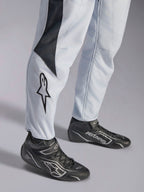 Alpinestars GP Pro Comp V2 FIA, combinaison de course auto grise et noire, bas des jambes avec logo et bottines de racing.