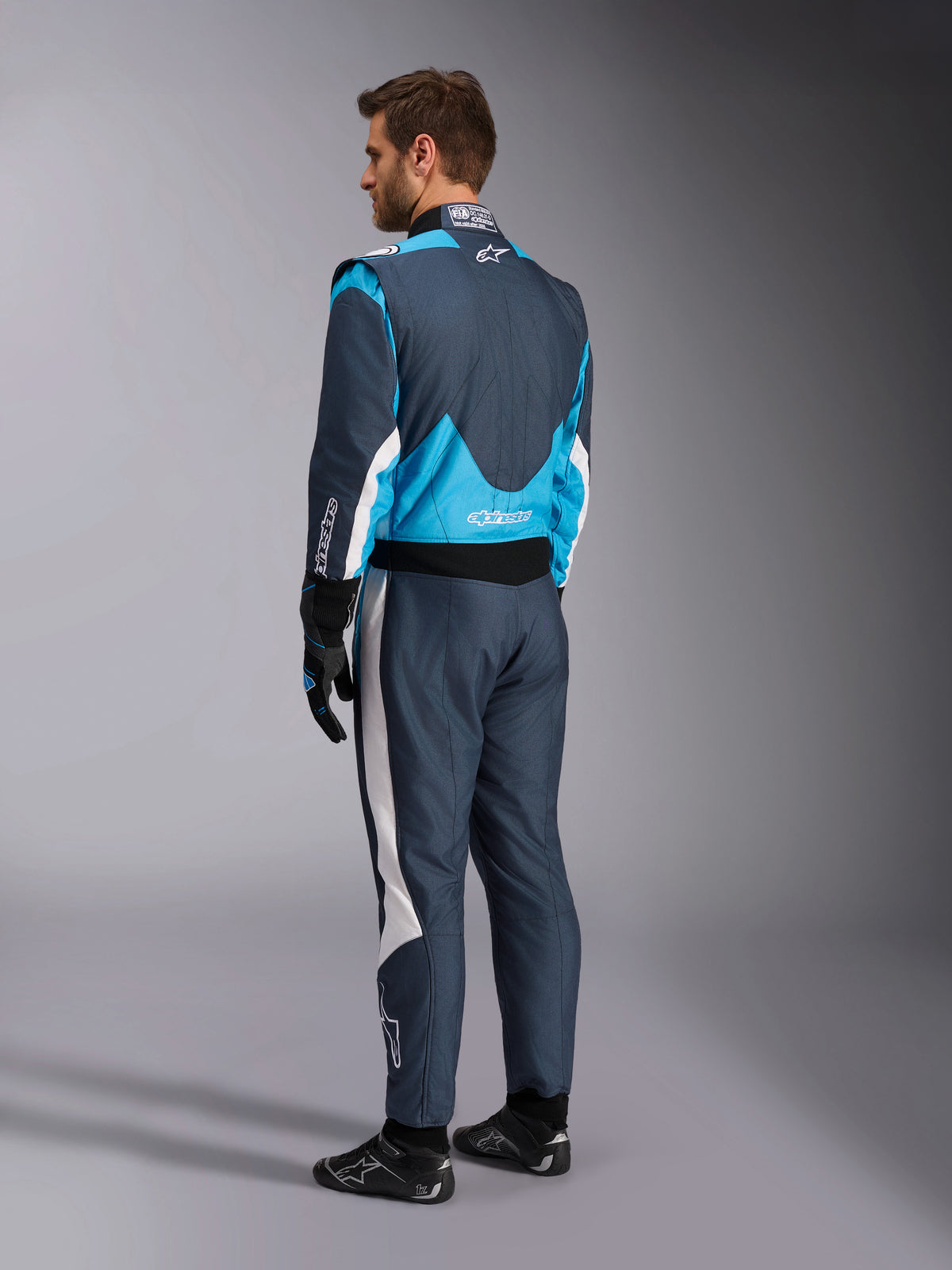 Combinaison Alpinestars GP Pro Comp V2 FIA, combinaison de course, gris asphalte et bleu cyan, vue de dos, mannequin équipé.