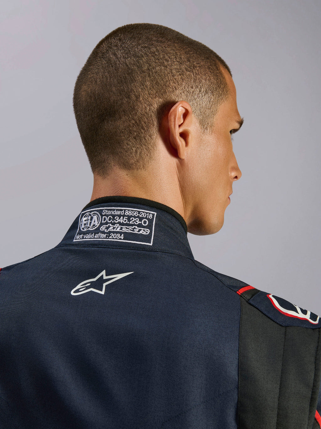 Combinaison Alpinestars GP Tech V4 en Bleu Marine Noir Rouge, gros plan sur le col arrière présentant l'étiquette de certification FIA 8856-2018 et le logo Alpinestars blanc brodé, détail de combinaison de course automobile haute performance