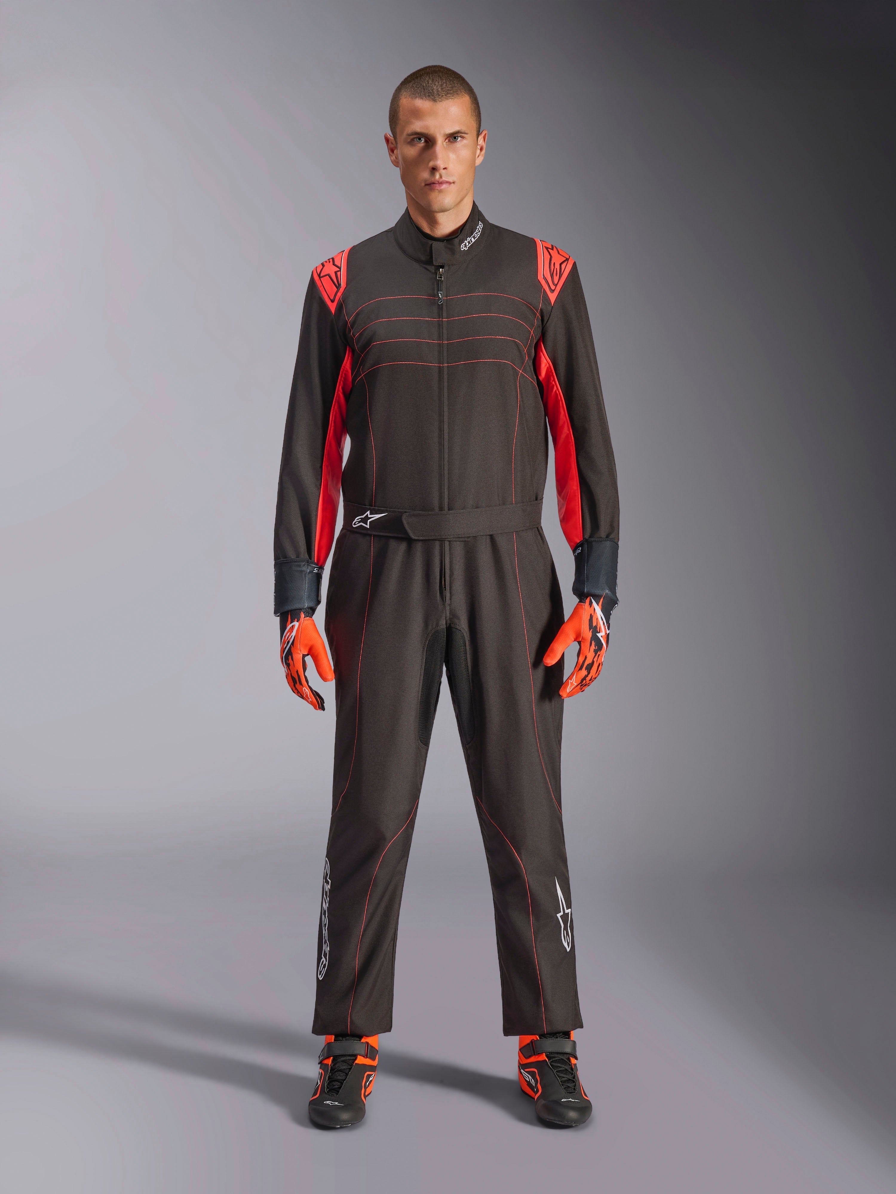 Combinaison de karting Alpinestars KMX-9 V3, noir et rouge fluo, combinaison de course une pièce portée avec des gants et des bottes coordonnés, avec des accents et des surpiqûres rouge vif sur les épaules, logo Alpinestars sur le bas des jambes, design motorsport élégant pour la course sur piste