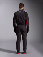 Combinaison Alpinestars KMX-9 V3 Graphic 3, combinaison de karting, noir et rouge, vue arrière présentant le panneau extensible lombaire et l'étiquette d'homologation FIA sur le col, accompagnée de gants de course noirs et de bottes aux accents rouges