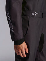 Close-up detail of the Alpinestars KMX-9 V3 Graphic 3 Suit in black, highlighting the adjustable waist belt with white logo, vertical branding on the sleeve, and knitted wrist cuffs.