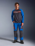 Alpinestars Maxdura Dual Jersey, maillot de moto, gris foncé et bleu royal, torse en maille intégrale avec manches rembourrées et poches poitrine zippées, logo Alpinestars blanc et orange, porté avec un pantalon d'aventure assorti et des bottes noires