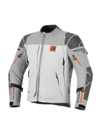 Veste Alpinestars Nazca 3L GORE-TEX PRO, veste de moto aventure, gris foncé et gris moyen avec des touches d'orange sur les fermetures éclair, arborant le logo All Terra sur la poitrine, renforts Superfabric aux épaules et aux coudes, multiples ouvertures de ventilation zippées, design touring robuste