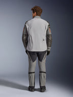 Veste Alpinestars Nazca 3L GORE-TEX PRO, vue arrière, gris foncé et gris moyen, veste de moto d'aventure avec construction GORE-TEX, logo rouge sur le col, détails orange sur les manches, portée avec un pantalon de moto assorti et des gants noirs.