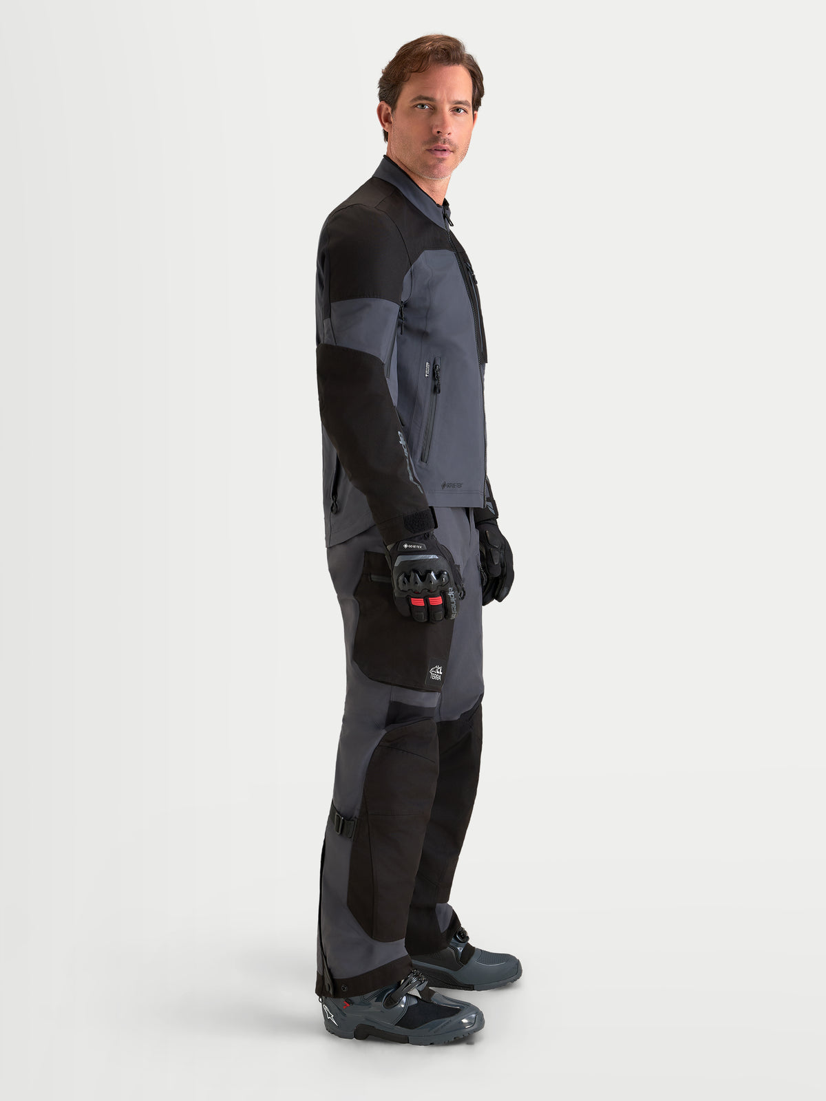 Alpinestars Arenis Gore-Tex® Gear Set, tenue complète d'aventure moto pour homme en noir et gris foncé, vue de profil sur un modèle portant l'équipement assorti avec construction en textile GORE-TEX imperméable
