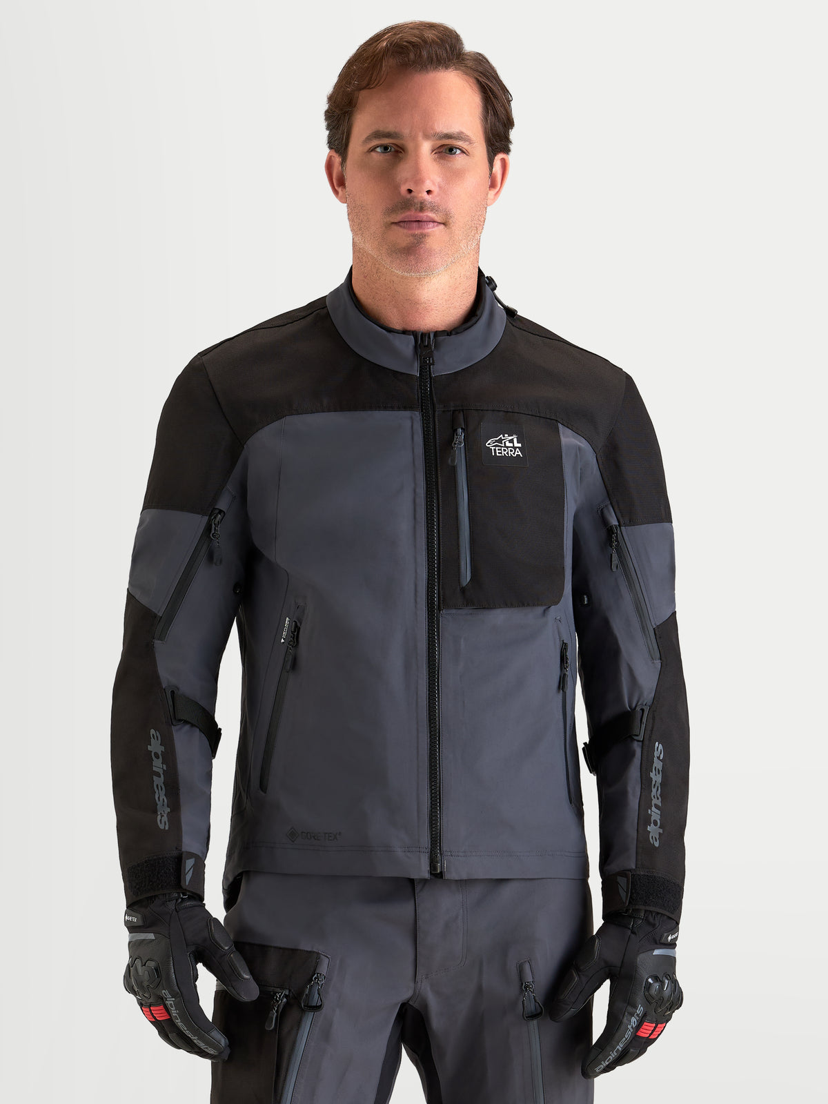 Alpinestars Veste Arenis Gore-Tex, veste de moto adventure pour homme noire et gris foncé, vue de face sur un modèle portant un équipement et des gants assortis