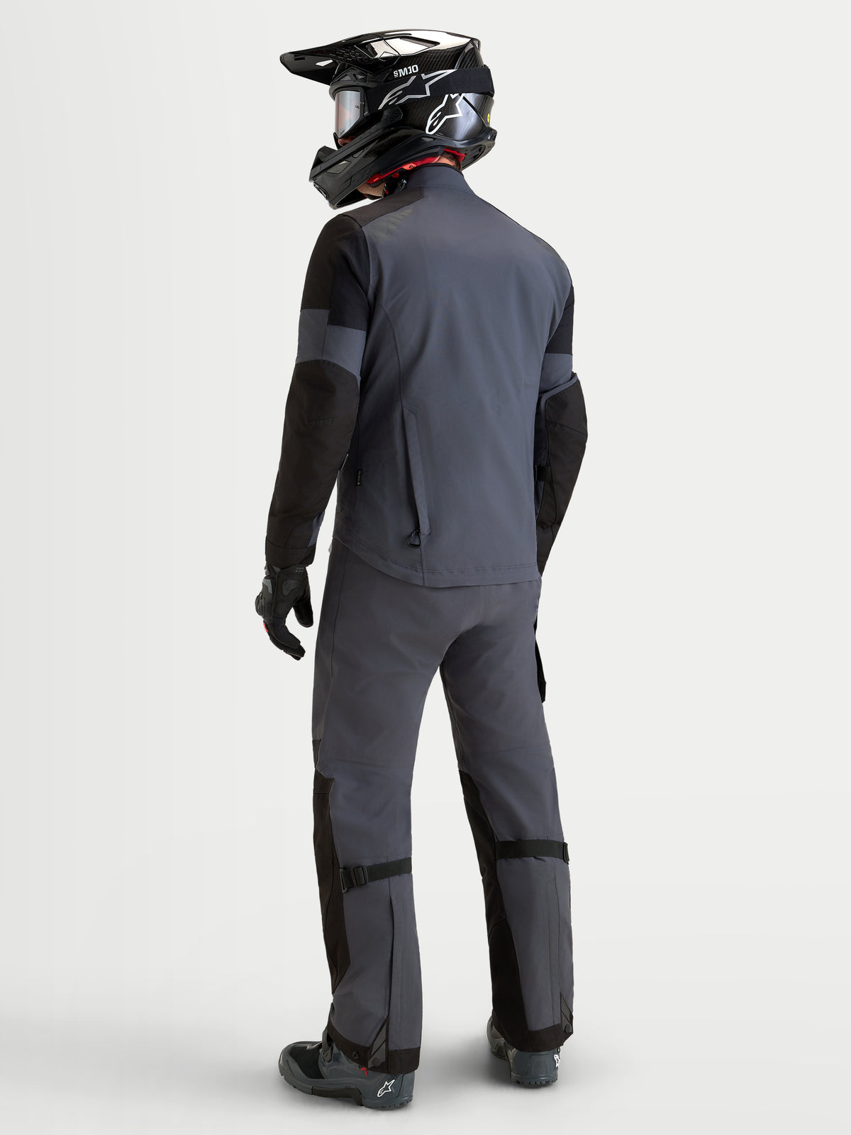 Alpinestars Tenue complète Arenis Gore-Tex, tenue de moto adventure pour homme gris et noir, vue de dos sur un modèle portant l'équipement assorti et un casque, vêtements de protection imperméables pour le tout-terrain