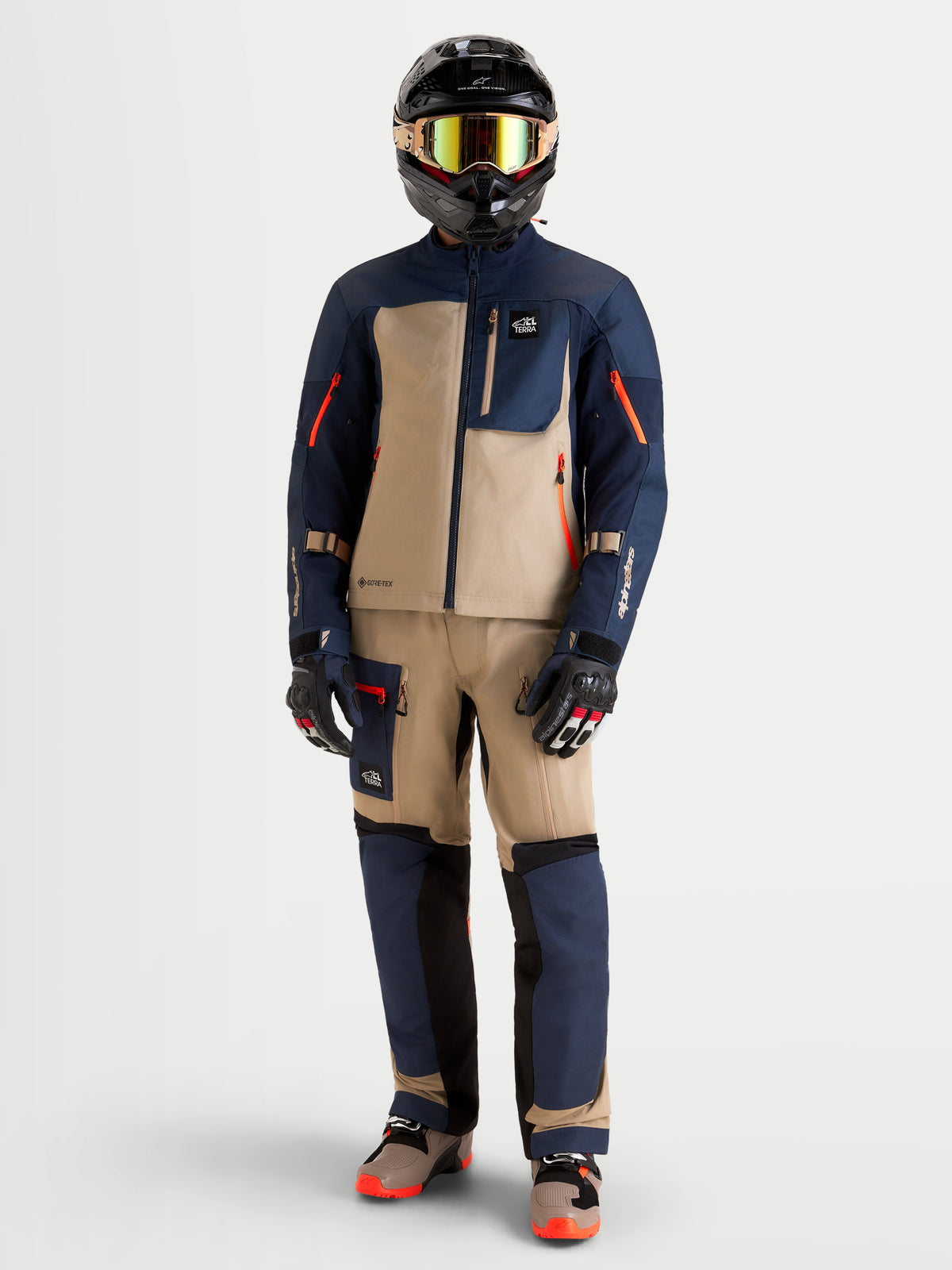 Alpinestars Arenis Gore-Tex Veste, veste de moto adventure pour homme en bleu marine et beige aluminium, portée par un pilote portant un équipement ADV et un casque assortis