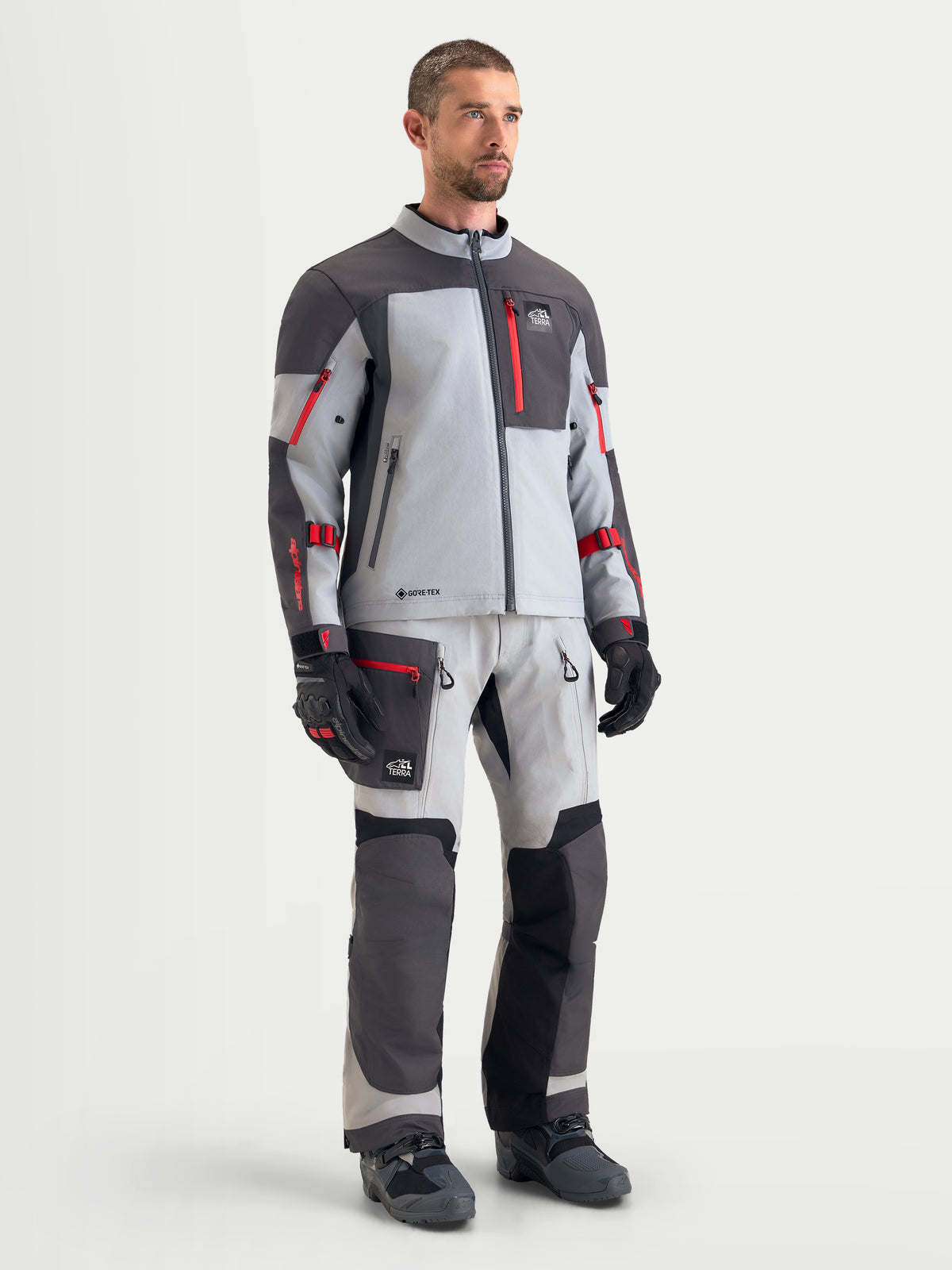 Alpinestars Arenis Gore-Tex Veste, veste de moto adventure pour homme en gris, gris foncé et noir, portée par un modèle masculin montrant la construction textile imperméable avec le pantalon et les gants assortis