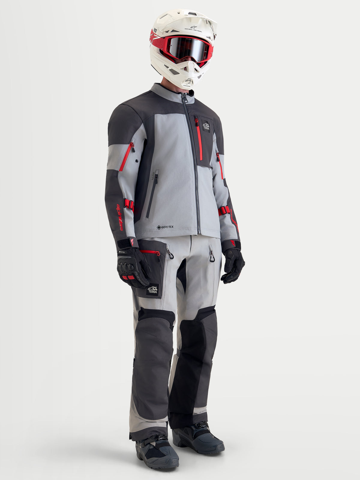 Alpinestars Arenis Gore-Tex veste, veste de moto adventure pour homme en gris moyen, gris foncé et noir avec des accents rouges, tenue complète avec pantalon assorti, casque et masque sur un modèle