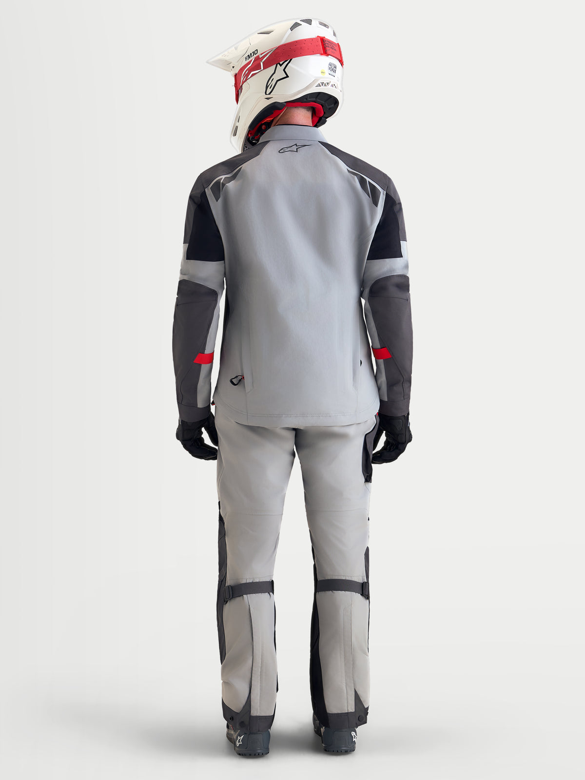 Alpinestars Veste Arenis Gore-Tex, veste de moto adventure pour homme en gris moyen, gris foncé et noir, vue de dos montrant un modèle portant la veste textile imperméable avec casque et équipement de moto