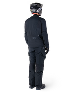 Vue arrière d'un pilote portant la veste Alpinestars St-7 Prime GORE-TEX noire, associée à un pantalon de touring noir assorti, un casque de moto noir avec logo blanc et des bottes de moto noires, équipement d'aventure protecteur complet pour le touring et les trajets quotidiens.