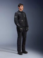 Pantalon Alpinestars ST-7 2L GORE-TEX, porté par un mannequin avec la veste ST-7 assortie, tenue de moto adventure touring entièrement noire, avec marquage GORE-TEX, poches cargo, gants et bottes noirs, prise de vue en studio sur fond gris