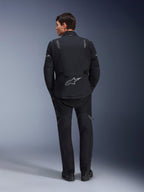Veste Alpinestars ST-7 2L GORE-TEX, veste de moto d'aventure, noir et gris foncé, vue arrière d'un homme portant la veste et un pantalon noir assorti, dotée d'un grand logo Astar réfléchissant dans le bas du dos, équipement textile imperméable pour le touring et la route