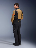 Veste Alpinestars ST-7 2L GORE-TEX, veste de moto d'aventure, brun Gobi et noir, vue arrière sur un mannequin portant un pantalon et des bottes de moto assortis, avec des accents orange sur les manches, coque laminée imperméable et logo Alpinestars, conçue pour le touring et la route