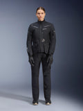 Motarde portant la veste et le pantalon Alpinestars Stella ST-7 2L GORE-TEX, tenue de touring moto noire pour femme, équipement technique imperméable et respirant, avec gants et bottes assortis, protection complète avec éléments réfléchissants pour le pilotage d'aventure