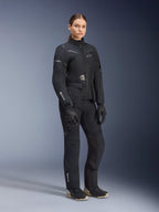 Mannequin femme portant une tenue d'aventure touring Alpinestars Stella ST-7 2L GORE-TEX, veste et pantalon noir et gris foncé, arborant le logo GORE-TEX sur la manche et la jambe, associée à des gants noirs et des bottes de moto, équipement de moto professionnel conçu pour le touring toutes saisons.