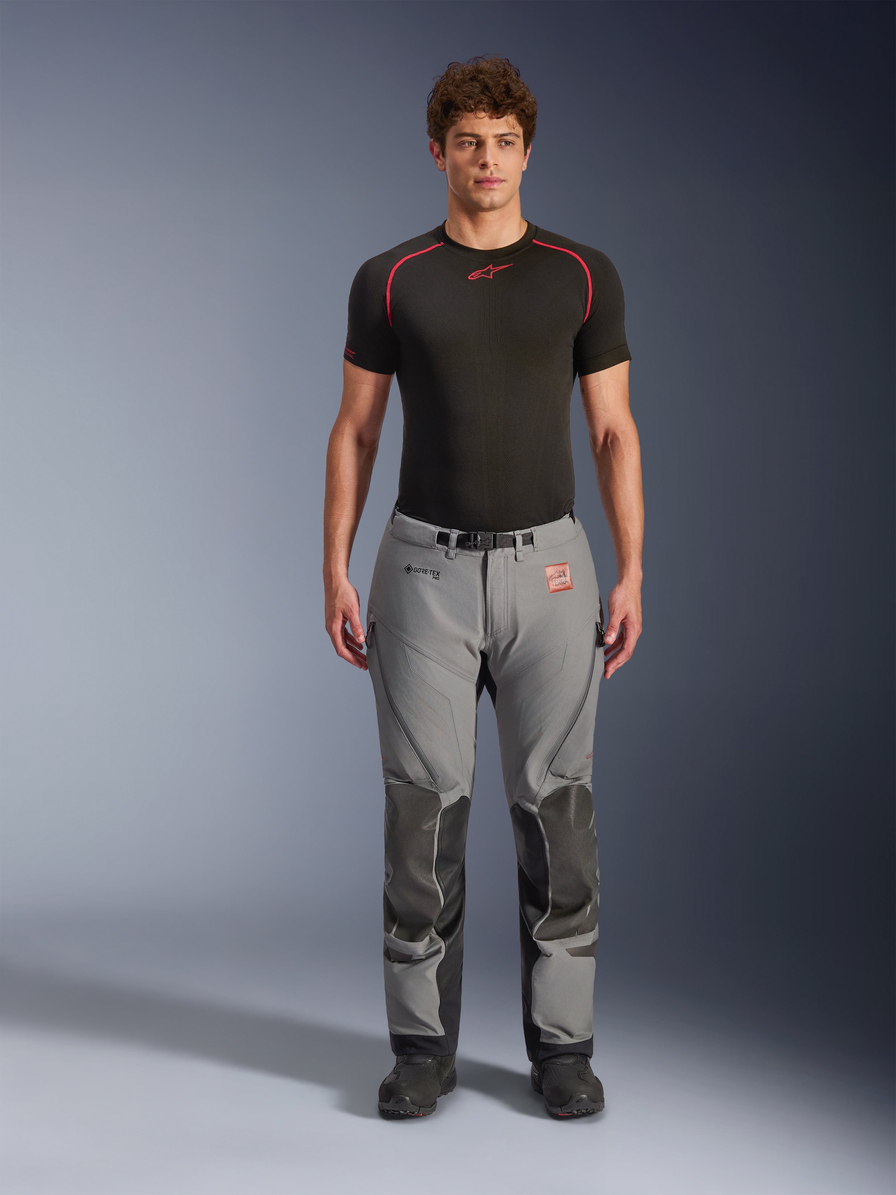 Pantalon Alpinestars Nazca 3L GORE-TEX PRO, pantalon de moto d'aventure, gris et noir, porté par un mannequin avec une couche de base noire, doté de panneaux de genoux renforcés, du logo GORE-TEX PRO et d'une conception textile robuste pour le touring toutes saisons