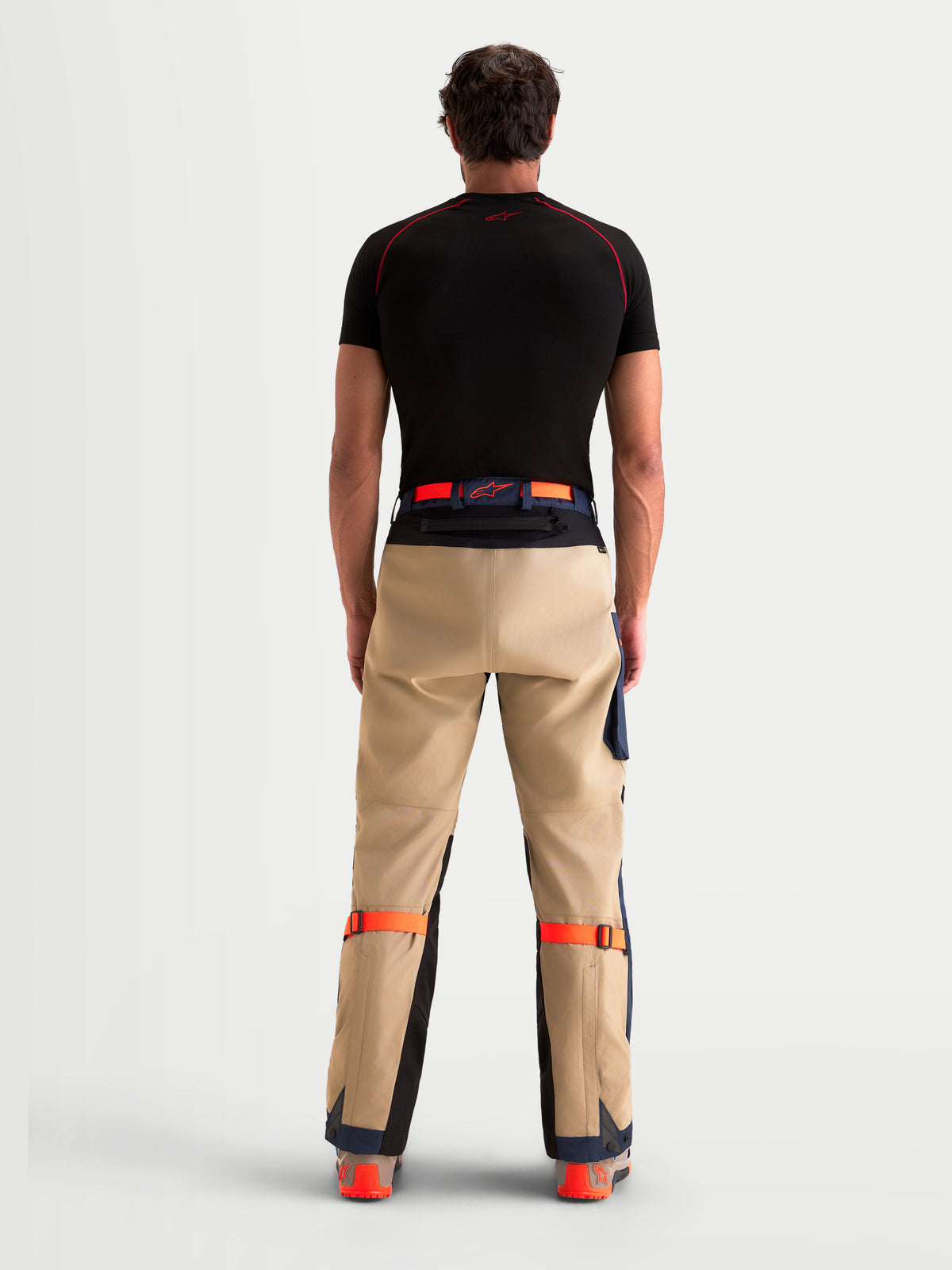 Alpinestars Arenis Gore-Tex Pantalons, pantalon de moto adventure pour homme beige et bleu marine, vue de dos sur un modèle montrant la fermeture à la taille et la construction renforcée de l'assise
