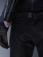 Pantalon Alpinestars ST-7 2L GORE-TEX, noir, gros plan sur la taille avec fermeture à boucle magnétique et construction textile technique durable, porté avec une veste de touring d'aventure assortie et des gants noirs au logo rouge.