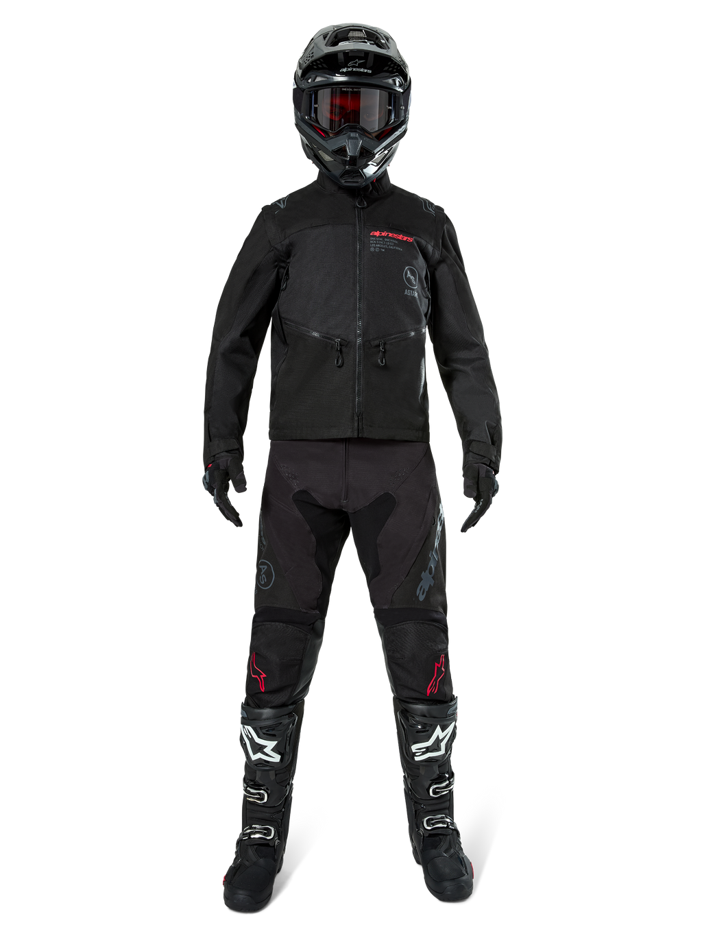 Veste Alpinestars Pro-Dura, veste d'enduro tout-terrain noire, présentée sur un modèle avec un équipement complet comprenant un casque noir avec des lunettes rouges, un pantalon noir avec des accents rouges, des bottes noires et blanches et des gants noirs, design robuste inspiré du rallye pour la conduite sur sentier