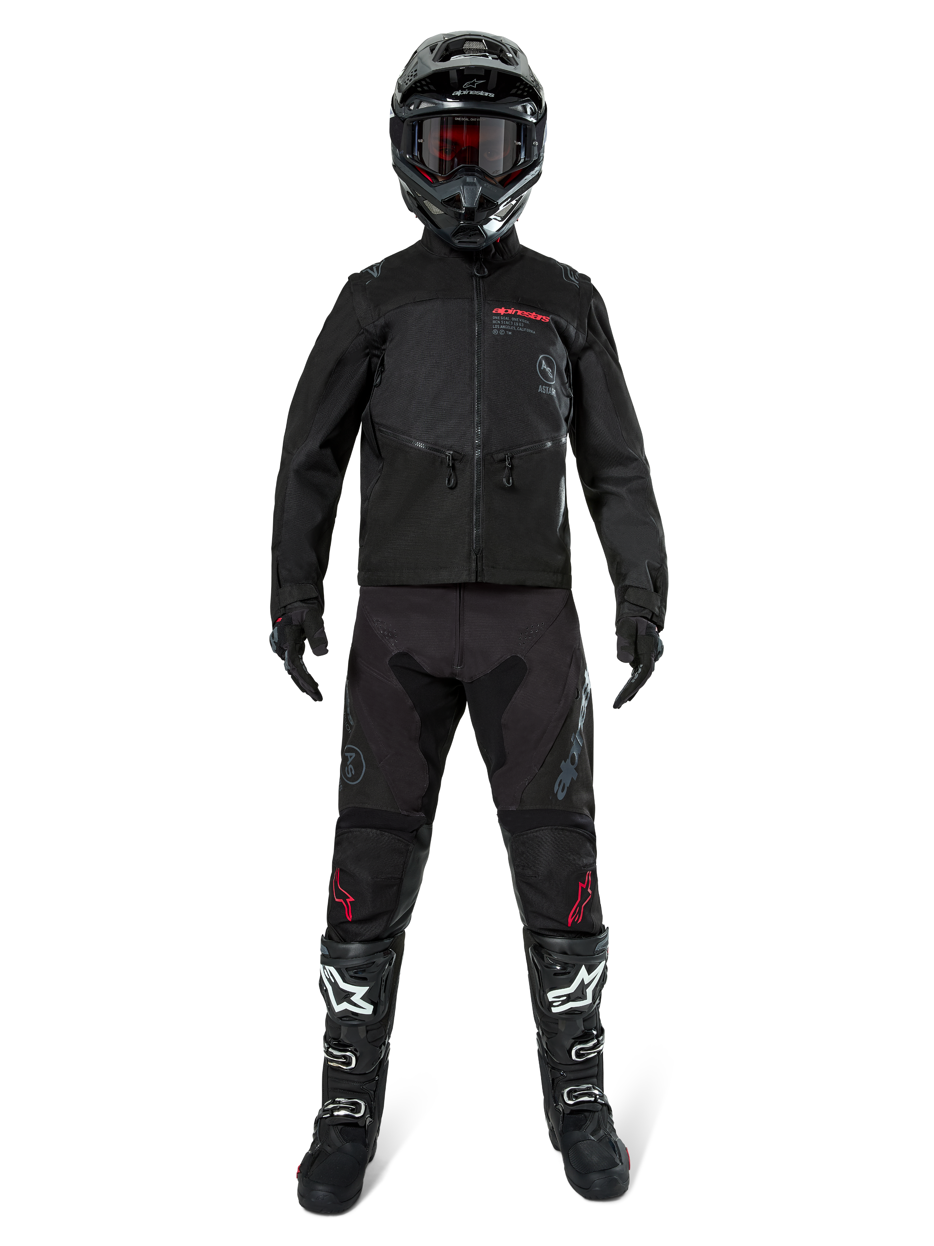Veste Alpinestars Pro-Dura, veste d'enduro tout-terrain noire, présentée sur un modèle avec un équipement complet comprenant un casque noir avec des lunettes rouges, un pantalon noir avec des accents rouges, des bottes noires et blanches et des gants noirs, design robuste inspiré du rallye pour la conduite sur sentier