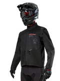 Alpinestars Pro-Dura Jacket, veste de moto tout-terrain, noire avec logos rouges et gris, dotée de poches avant zippées et d'un col montant, portée avec un casque de motocross noir et des gants pour l'enduro