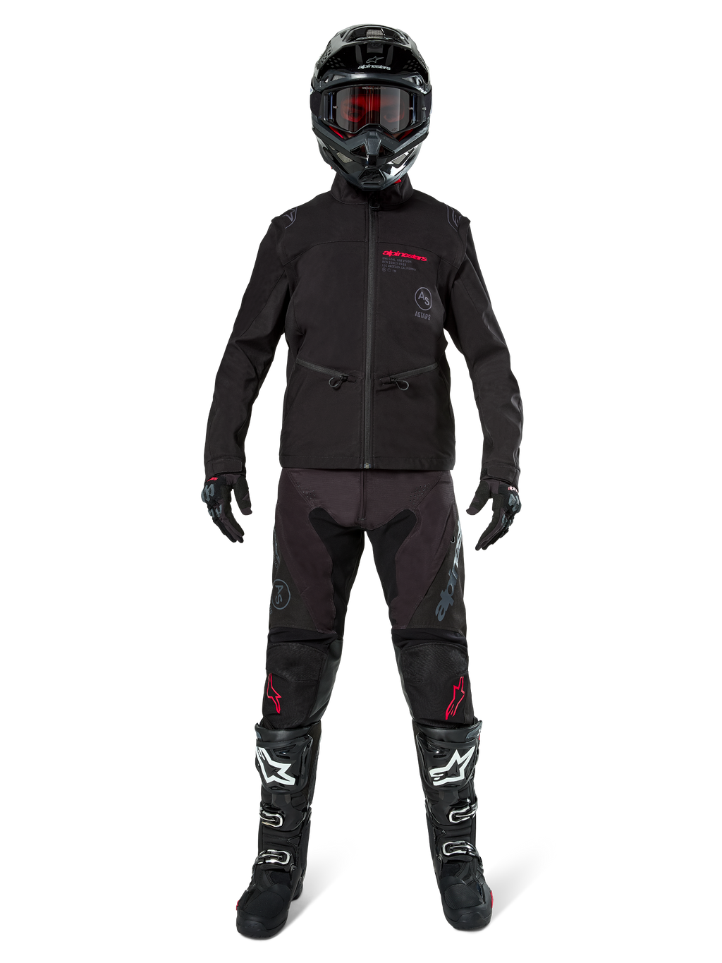 Pilote de motocross portant la veste softshell Alpinestars Lite-Dura noire avec des détails de logo rouges, associée à un pantalon tout-terrain noir assorti, un casque noir et des bottes blanches et noires, équipement complet de course enduro professionnel.