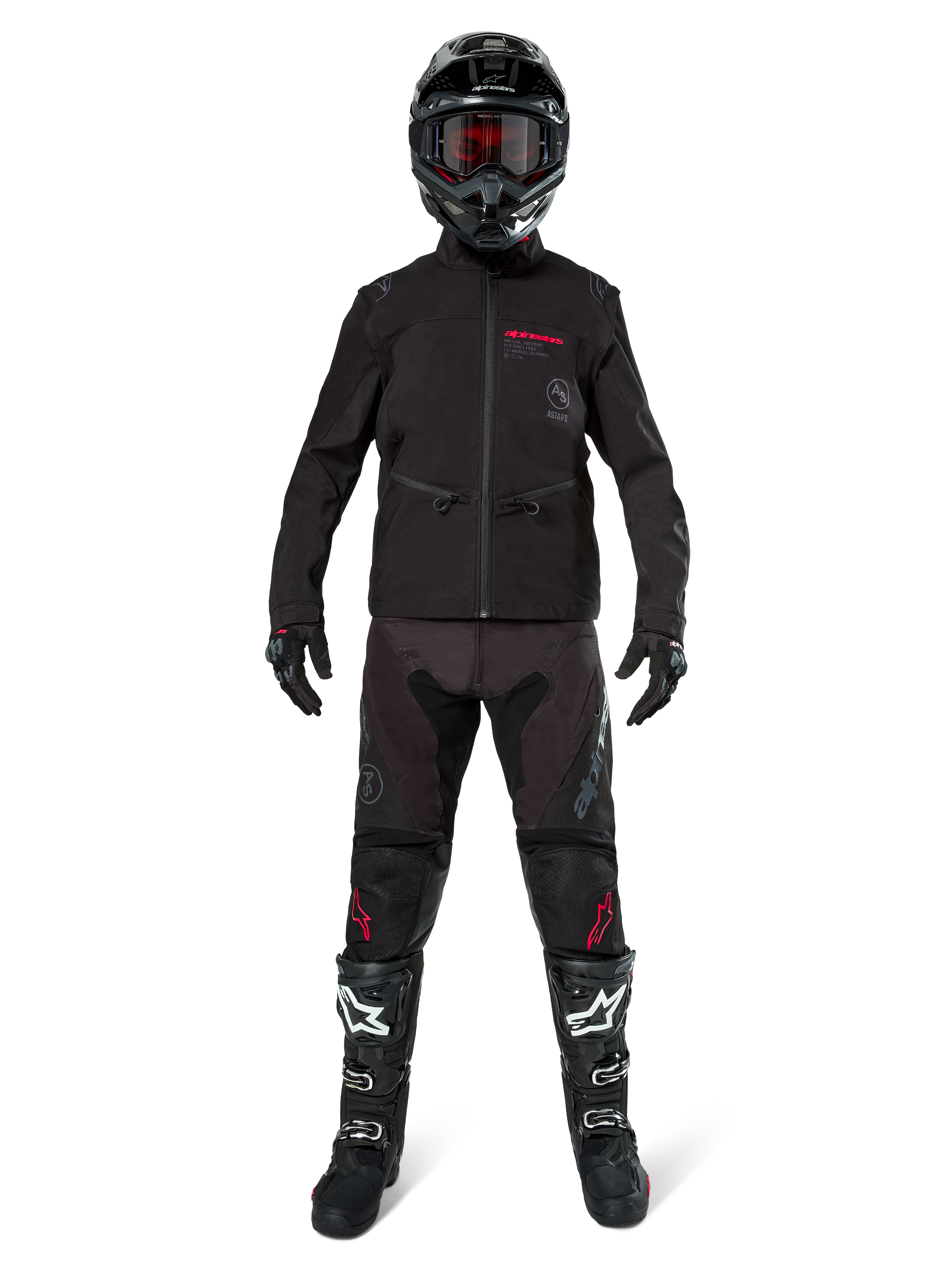 Pilote de motocross portant la veste softshell Alpinestars Lite-Dura noire avec des détails de logo rouges, associée à un pantalon tout-terrain noir assorti, un casque noir et des bottes blanches et noires, équipement complet de course enduro professionnel.
