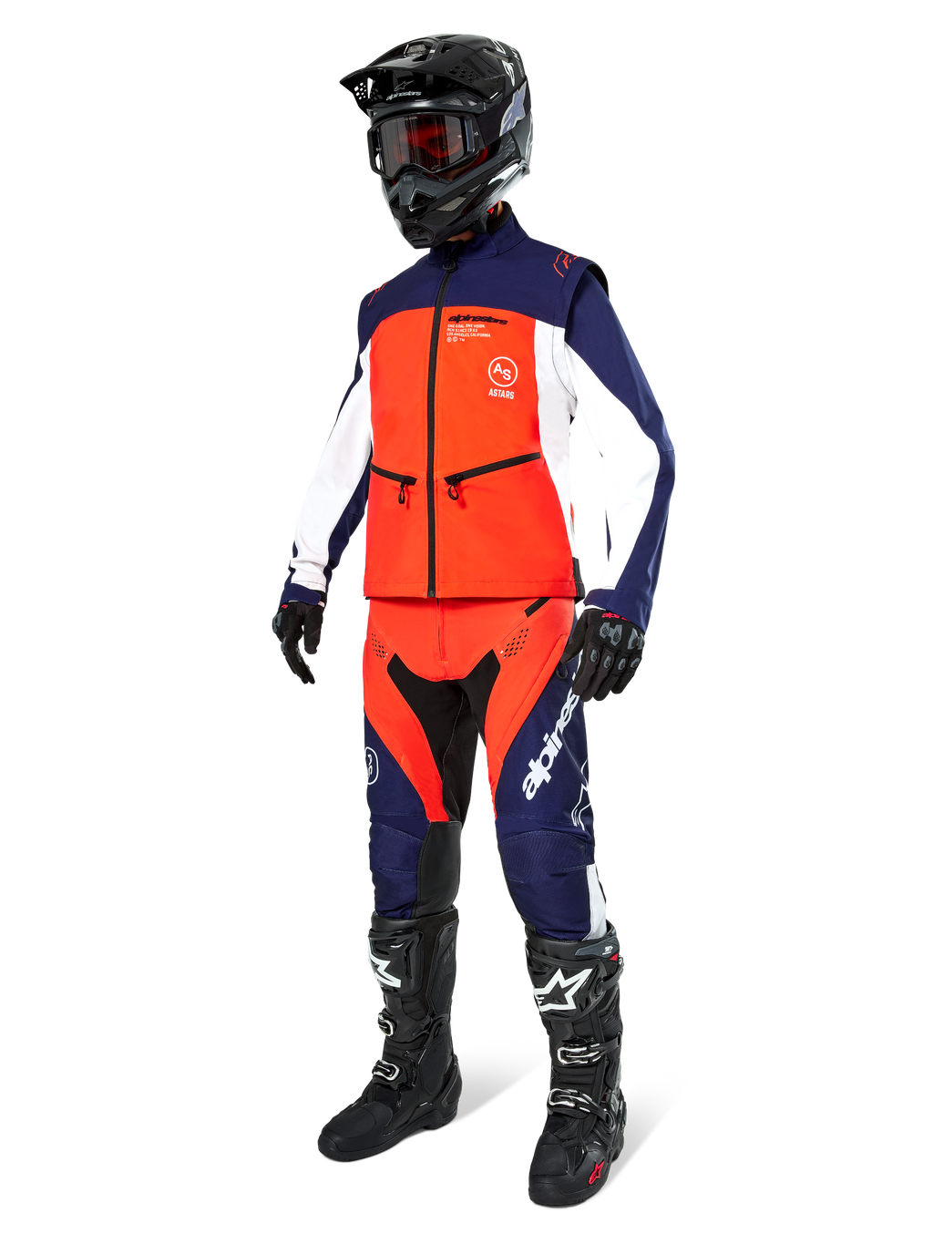 Pilote de motocross portant la veste Softshell Alpinestars Lite-Dura en Navy, Orange Vif et Blanc, avec pantalon tout-terrain assorti, casque noir avec lunettes et bottes de course noires, tenue d'enduro coordonnée