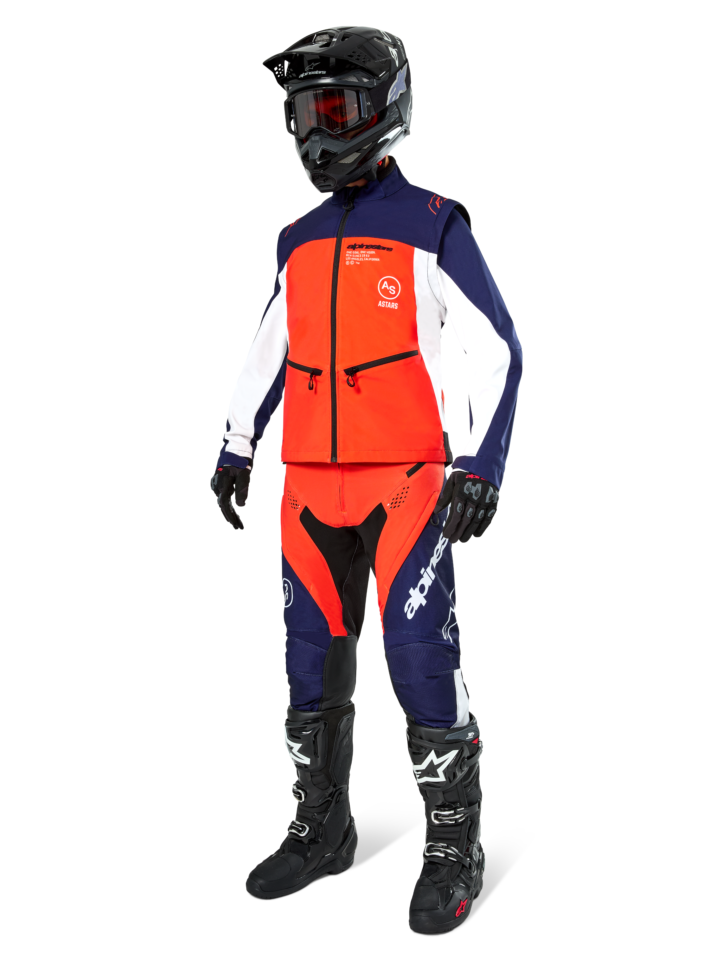 Pilote de motocross portant la veste Softshell Alpinestars Lite-Dura en Navy, Orange Vif et Blanc, avec pantalon tout-terrain assorti, casque noir avec lunettes et bottes de course noires, tenue d'enduro coordonnée
