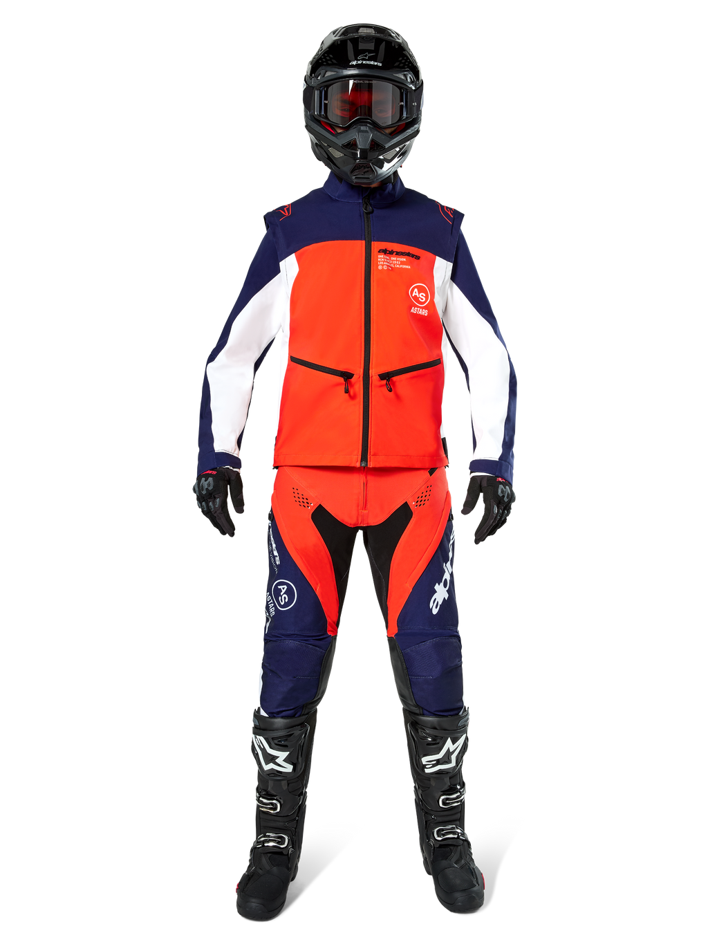 Pilote de motocross portant un équipement tout-terrain complet, veste Softshell Lite-Dura Alpinestars en bleu marine, orange vif et blanc, pantalon assorti marine et orange, casque noir avec lunettes, bottes noires et blanches, gants noirs, tenue coordonnée pour la course d'enduro.