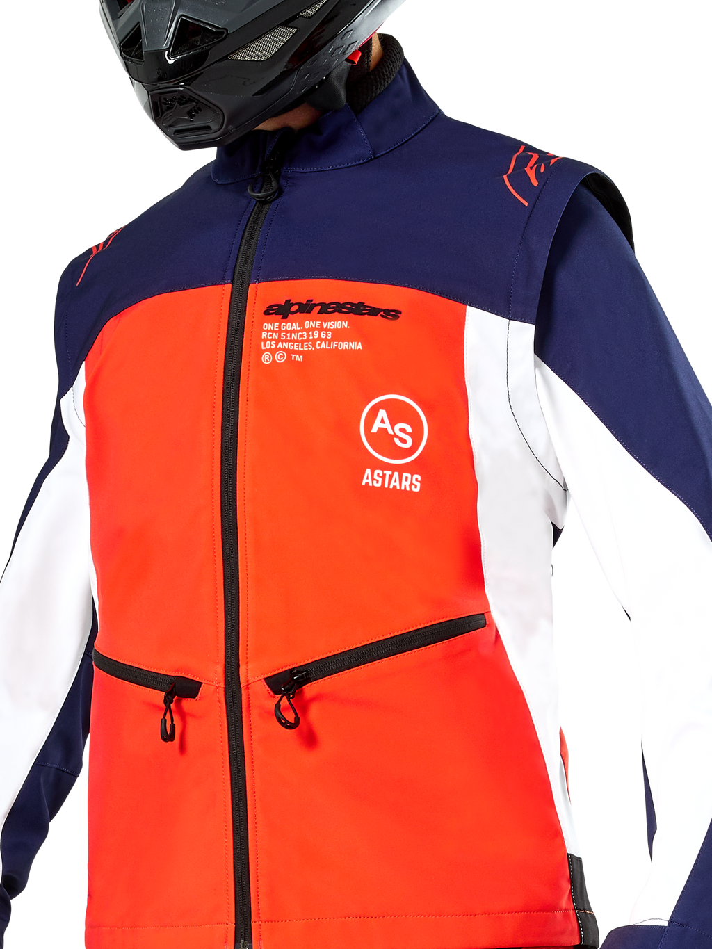 Veste Softshell Alpinestars Lite-Dura en bleu marine, orange vif et blanc, vue rapprochée du torse, empiècement frontal orange vif, panneaux latéraux blancs et épaules bleu marine, poches zippées, logo Alpinestars bien visible, portée par un pilote avec un casque tout-terrain noir
