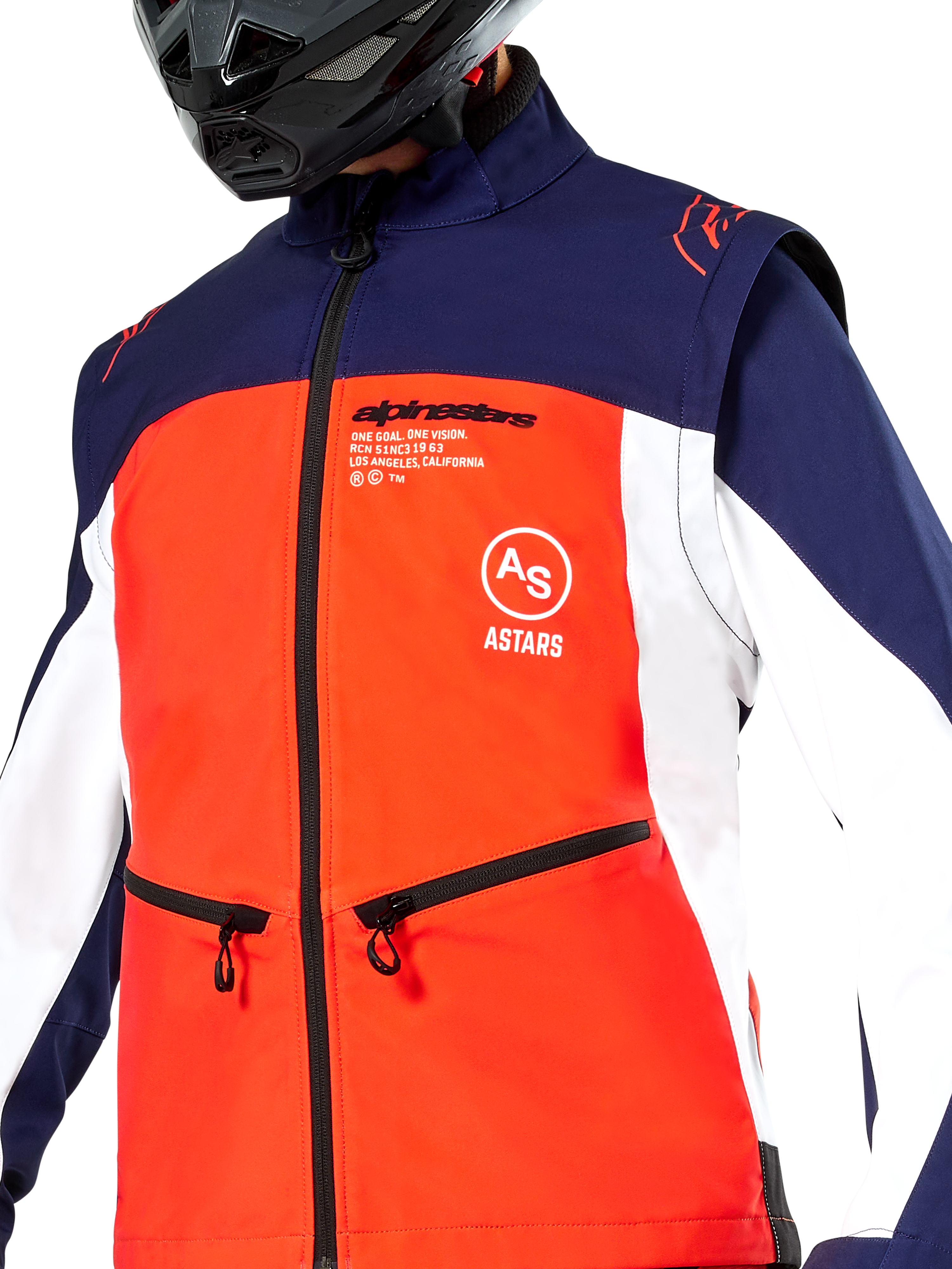 Veste Softshell Alpinestars Lite-Dura en bleu marine, orange vif et blanc, vue rapprochée du torse, empiècement frontal orange vif, panneaux latéraux blancs et épaules bleu marine, poches zippées, logo Alpinestars bien visible, portée par un pilote avec un casque tout-terrain noir
