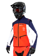 Veste Softshell Alpinestars Lite-Dura en bleu marine, orange vif et blanc, équipement de motocross, portée avec un casque et des lunettes noirs, des gants de protection et un pantalon de course assorti