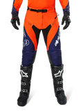 Pantalon Alpinestars Pro-Dura, pantalon de motocross et d'enduro, bleu marine, orange vif et blanc, avec empiècements noirs et logos blancs, porté avec des bottes et des gants tout-terrain noirs, équipement de protection professionnel pour le trail et le tout-terrain
